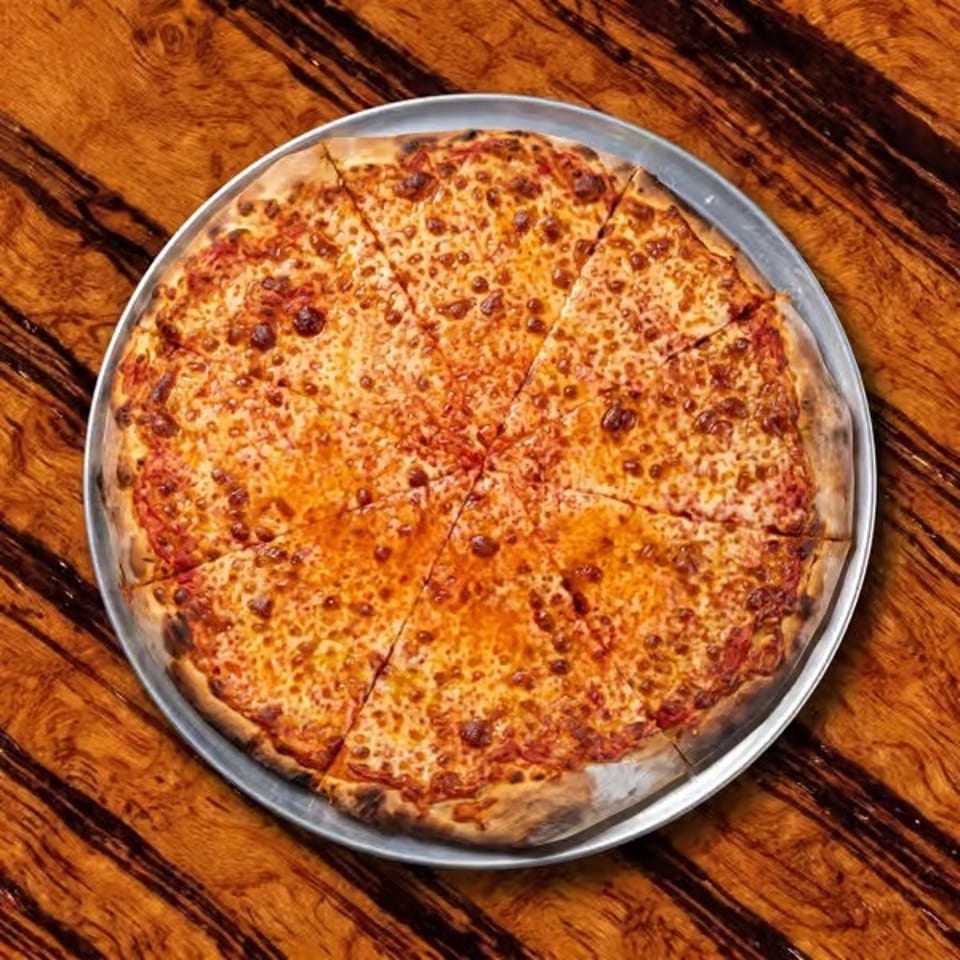 Round cheese pizza sliced into wedges on a metal tray atop a rustic wooden table.